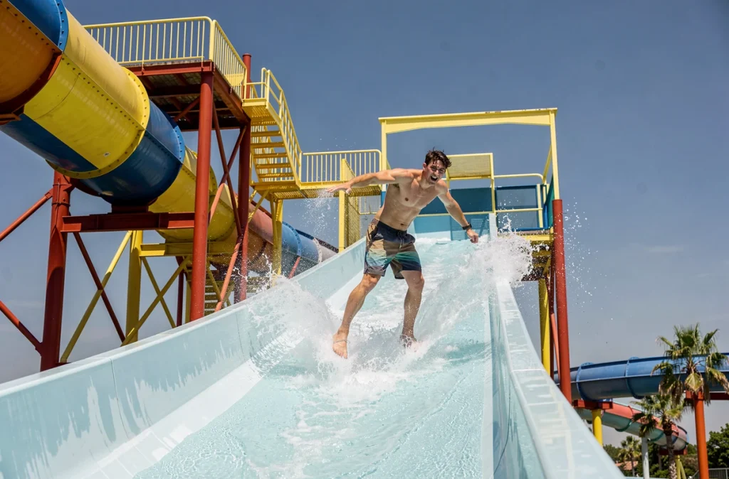 Jeune homme en short de bain s'élançant avec enthousiasme sur le toboggan à grande vitesse du SpeedWater Park