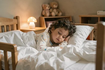 Enfant de 4 ans endormi dans son lit avec une petite veilleuse posée sur la table de nuit, illustrant l'importance du choix de la veilleuse pour le sommeil des jeunes enfants